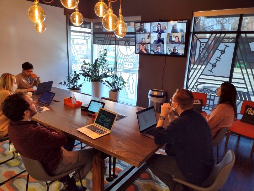The Reverb marketing team having a meeting in a conference room with a video conference screen. 