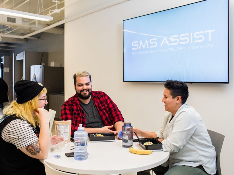 SMS Assist team chats a table together
