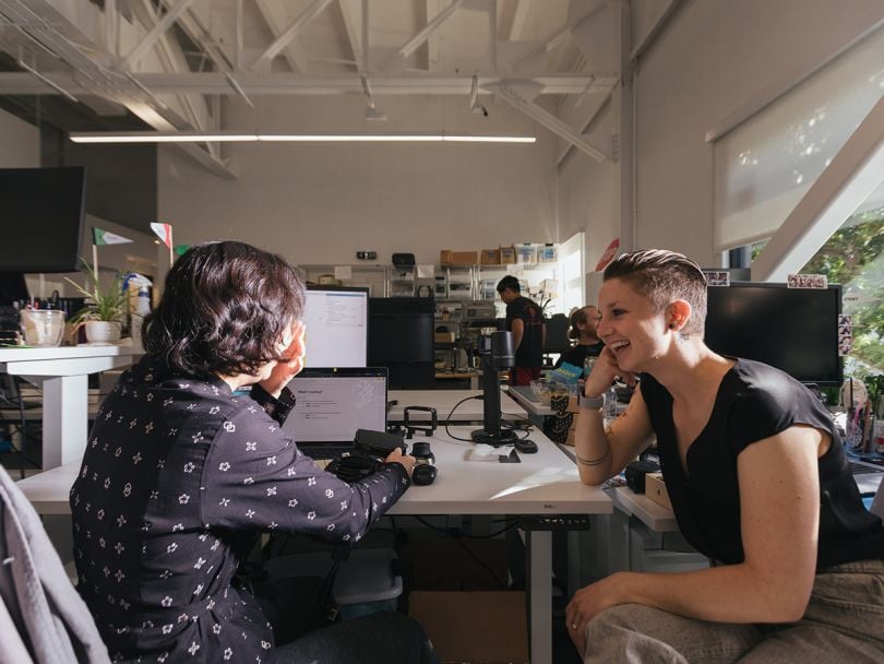Two Samasara team members smiling workign on a project together in the office