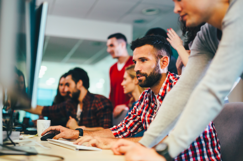 an engineering team huddles in front of a computer