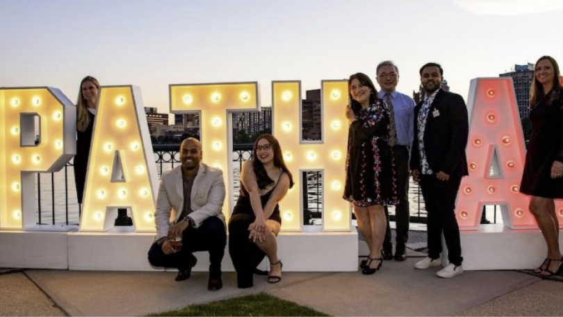 PathAI team members pose next to an illuminated sign of the company’s name. 