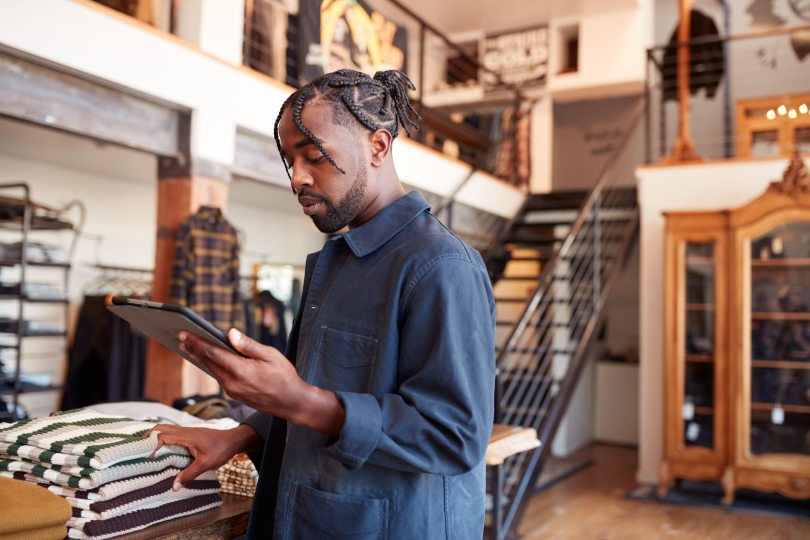 A fashion store owner checking online orders and inventory on a tablet.