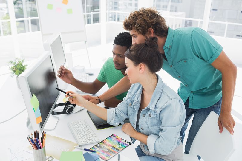 Side view of three designers working on computer at the office