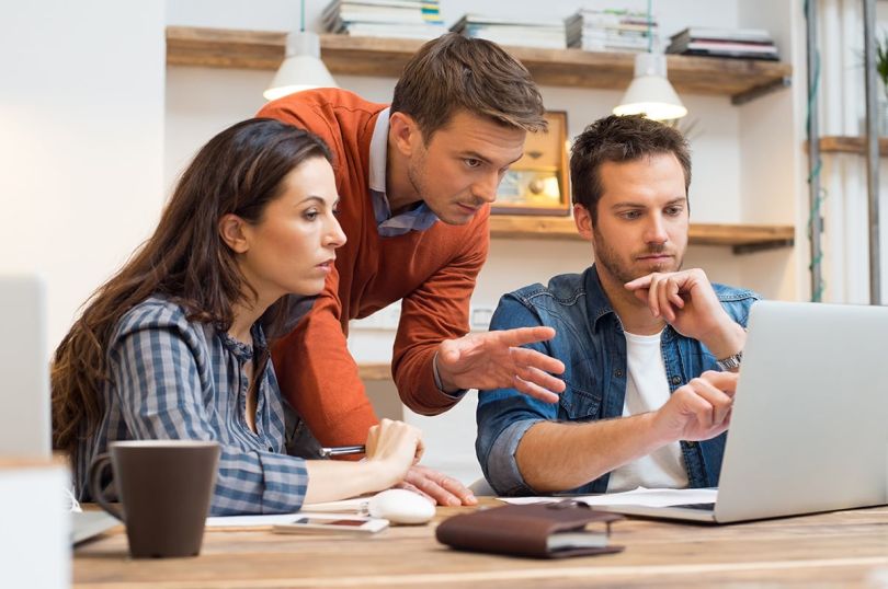 Businesspeople having a discussion while looking at a laptop