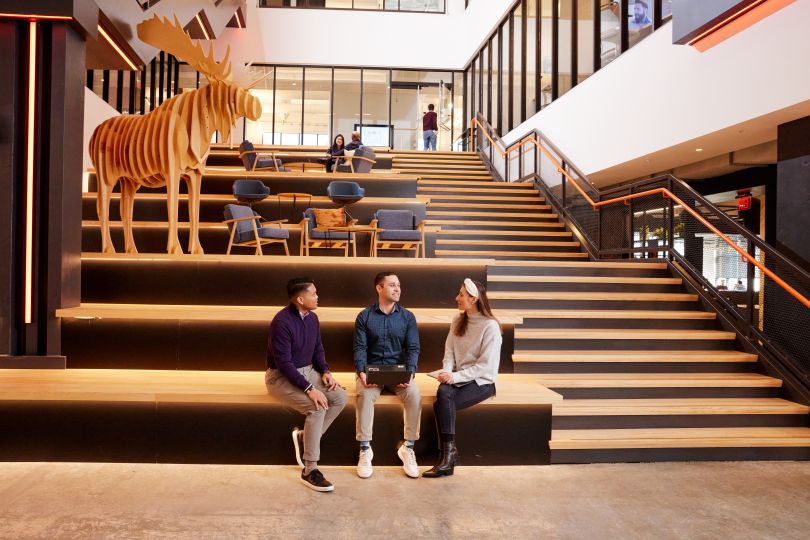 Three coworkers sit in a common area.