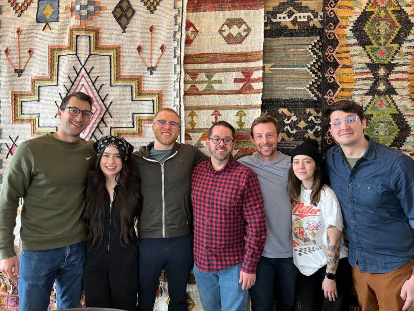 seven people taking a group photo in front of colorful wall