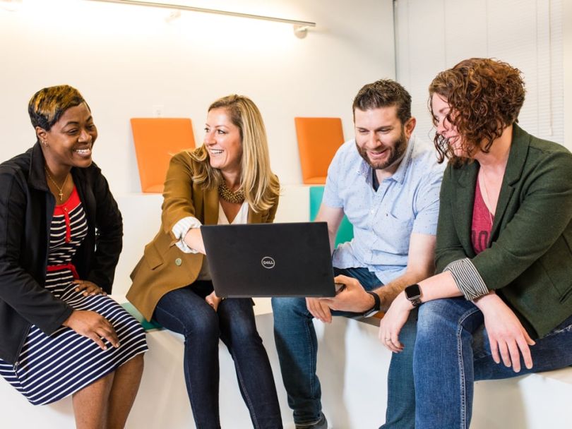 A group of Epsilon employees work together on a couch