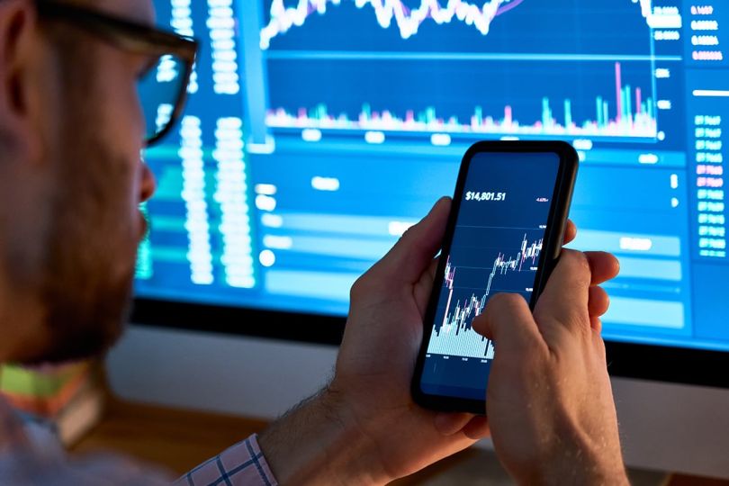 Business man trader investor analyst using mobile phone app analytics for cryptocurrency financial stock market analysis&nbsp;