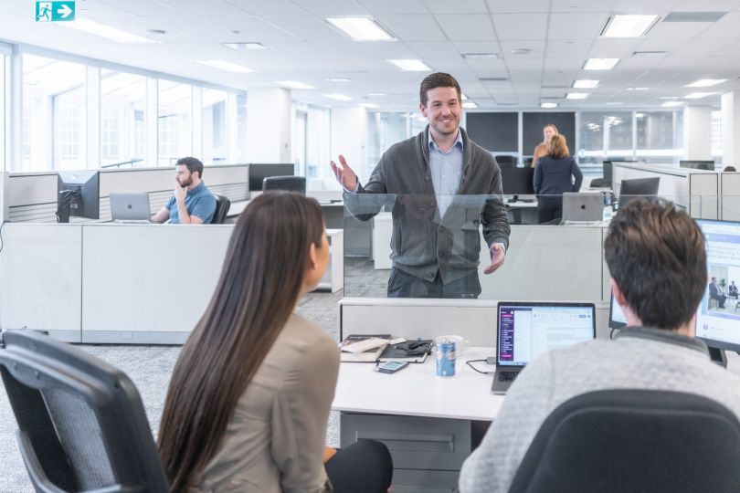 Validere team talking in the office with glass cubicle walls.