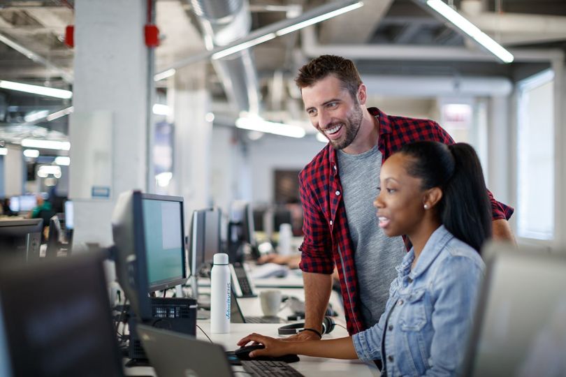 VelocityEHS coworkers in the office looking at a computer moniotr