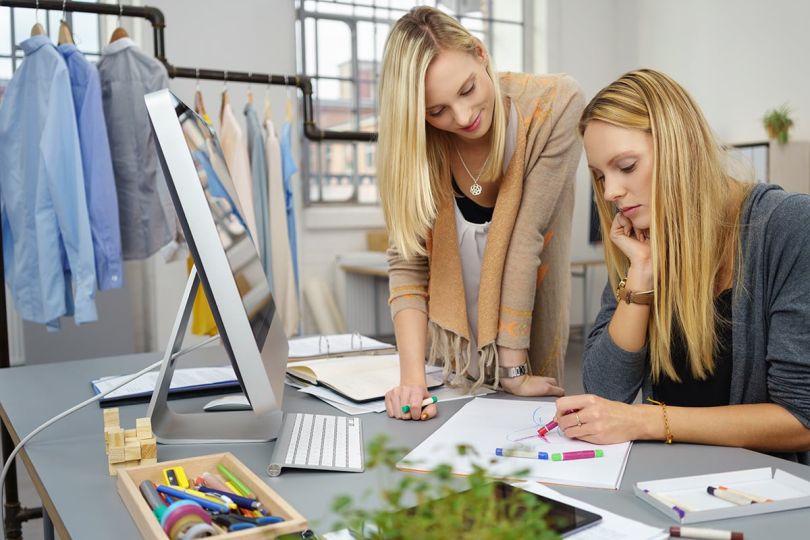 Coworkers chatting in an office surrounded by clothing. 