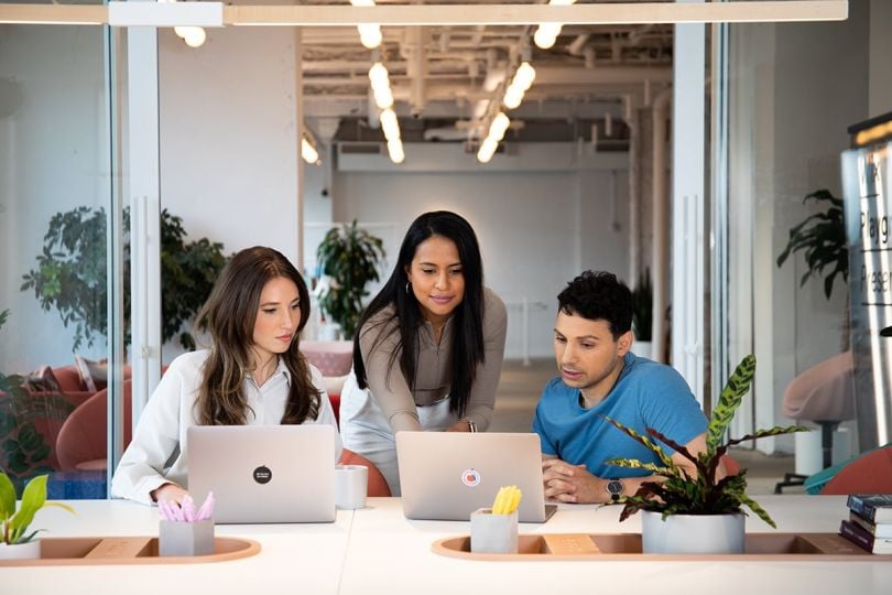 Wix coworkers having a team huddle looking at laptops
