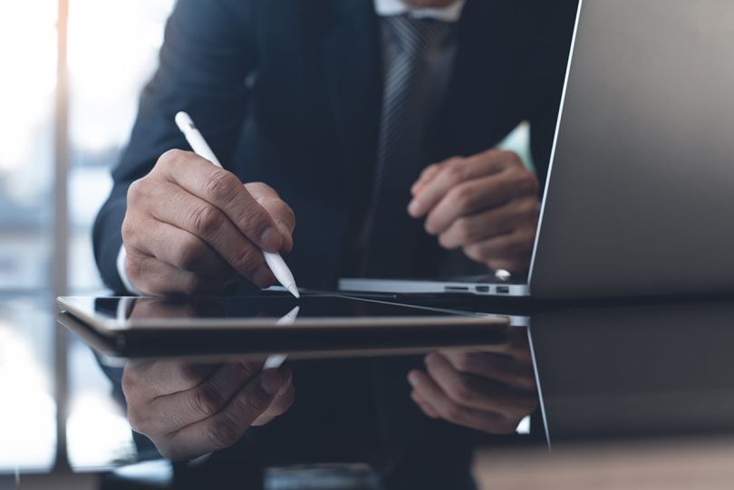 Business man with stylus pen signing on digital tablet screen