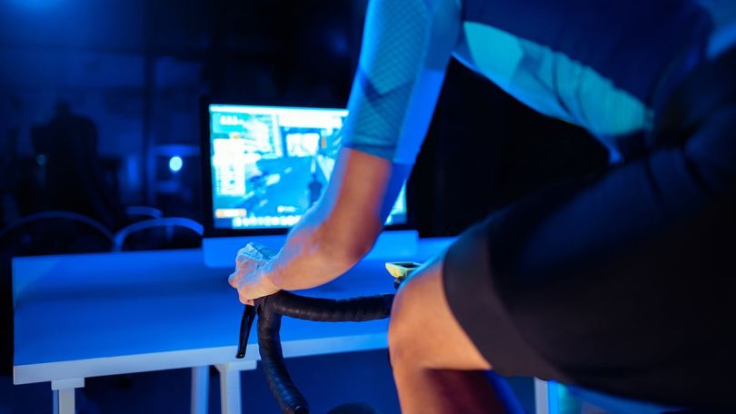 man cycling on an exercise bike with a virtual trainer