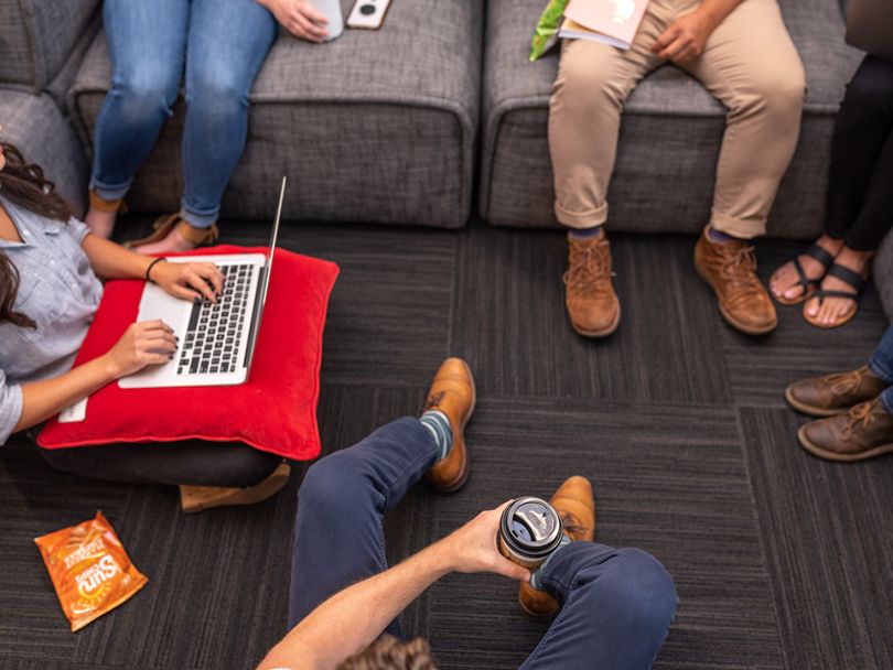 Photo of AlertMedia employees sitting near a sofa