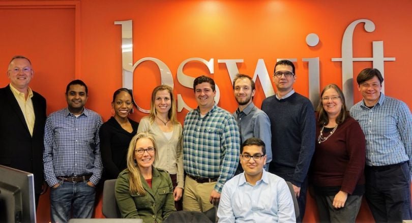 A team photo bswift pictured in front of their logo
