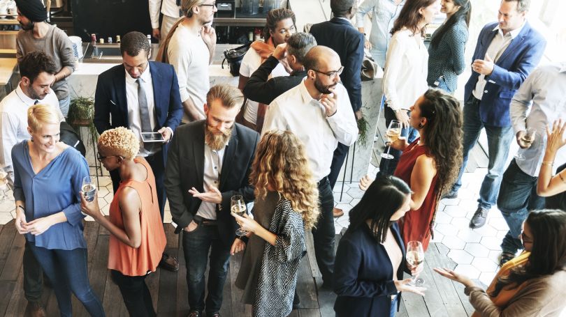 A gathering of people at a networking event is shown.