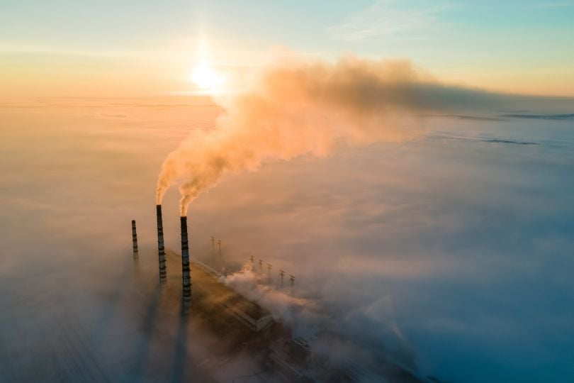 A smokestack emitting CO2 is pictured.