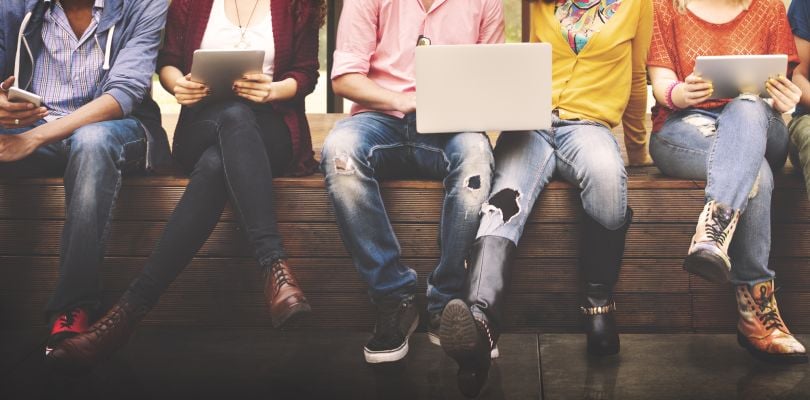 College students are pictured sitting with laptops and books.