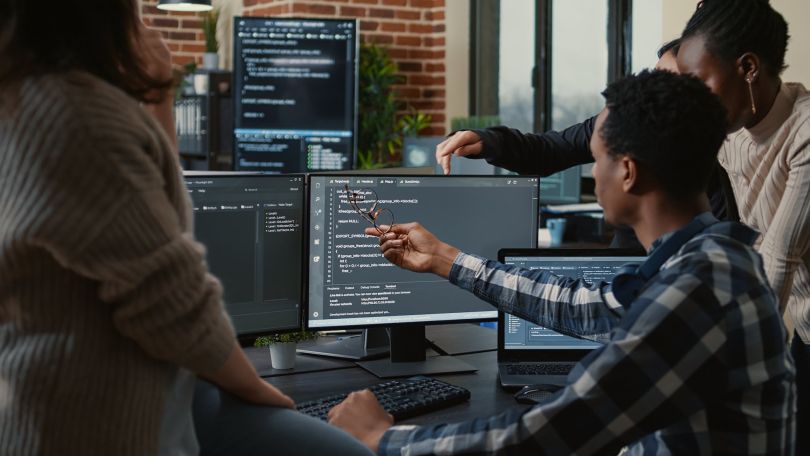 A group of developers discusses computer code.