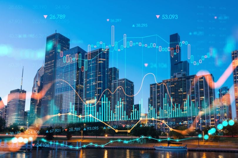 A cityscape overlaid with colorful graphs and numerical data, representing financial market trends.