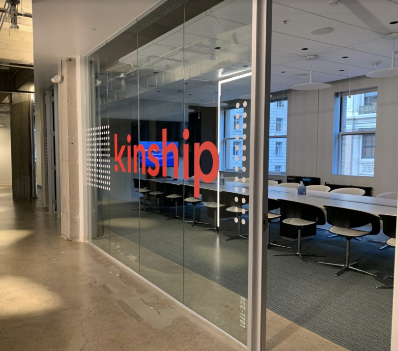 A look into Kinship's meeting room from the outside. The company logo is printed on the glass window.