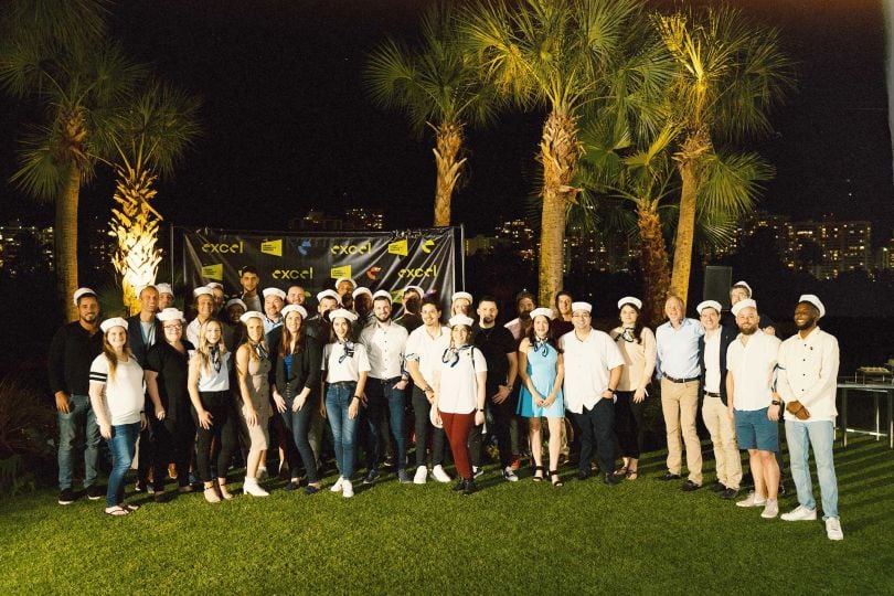 The Excel team pictured as a group in front of palm trees