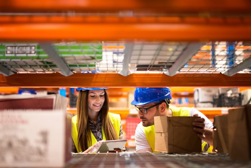 Close up view of shelf with products and workers in storage department