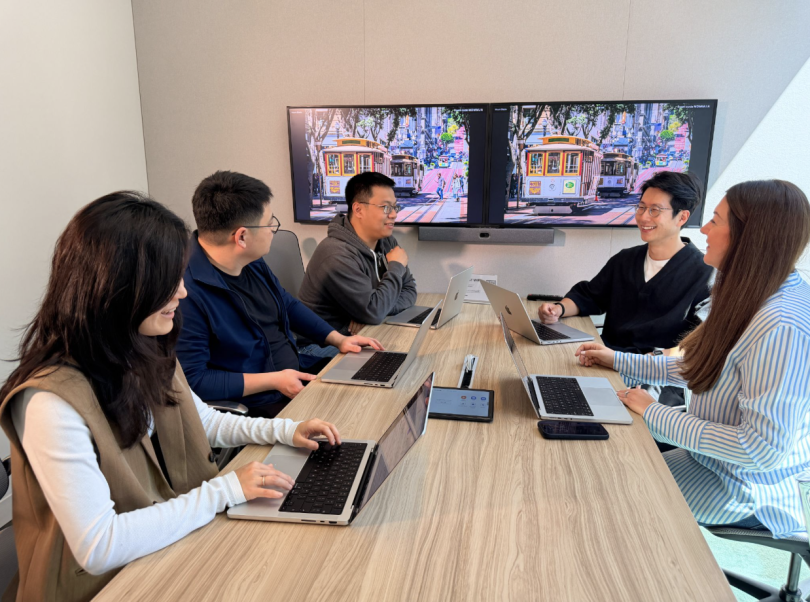 Several Airwallex employees chat during a meeting in an conference room in one of Airwallex's offices.