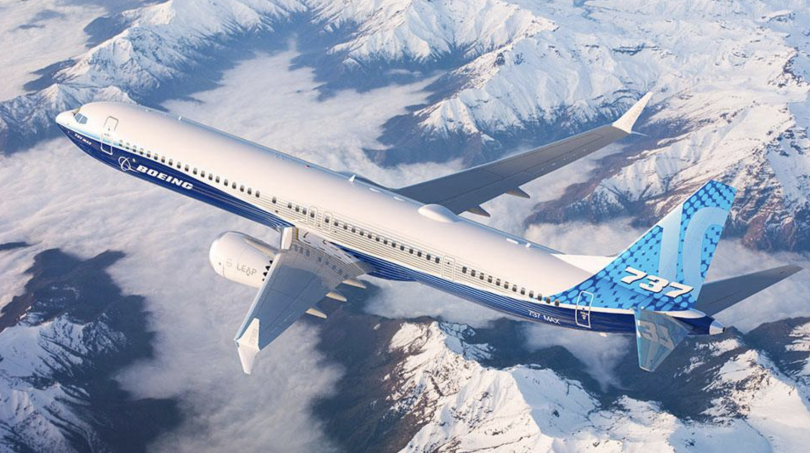 A Boeing airplane flying over snow-capped mountains