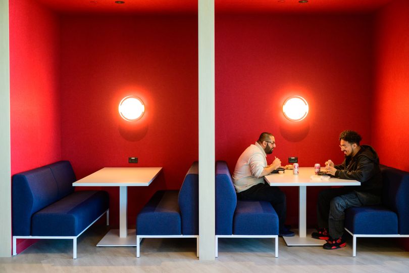 Two CarGurus employees meet in a cafe booth in the company’s new global headquarters inside Boston’s new Lyrik Back Bay project at 1001 Boylston Street.&nbsp;