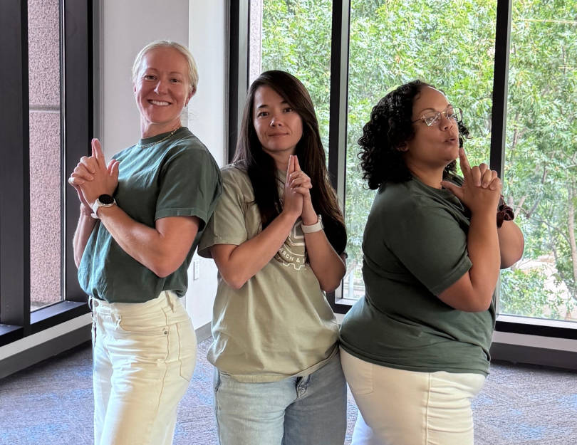 Kris McKee and two colleagues striking “finger gun” action poses for a photo during a company event.