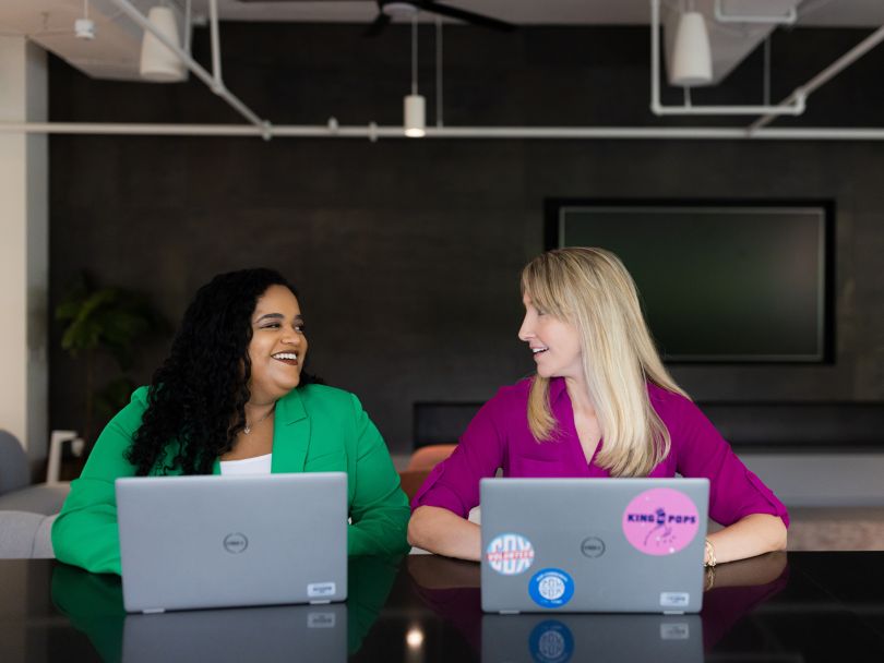 Two Cox Enterprises work on their laptops together in the company's office