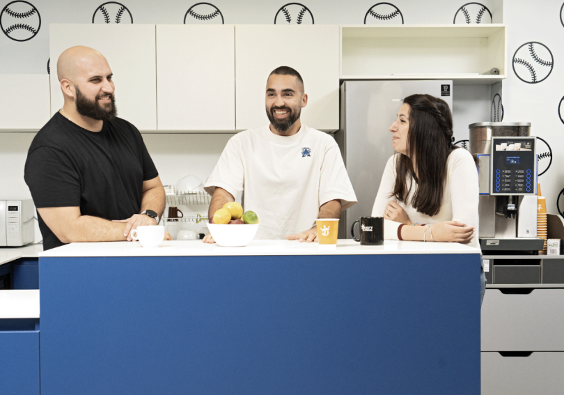 Three DraftKings team members chat in the kitchen area of the company’s office