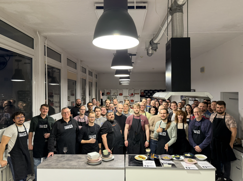 A large group of Dropbox employees pose for a group photo while wearing aprons during a cooking class