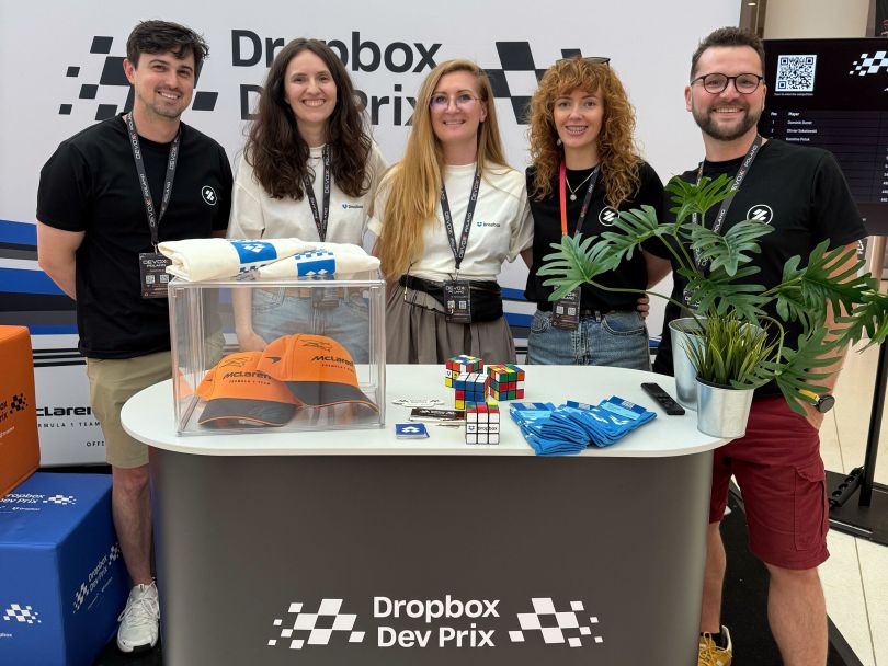 Five Dropbox employees pose for a group photo behind a promotional stand during the Dropbox Dev Prix