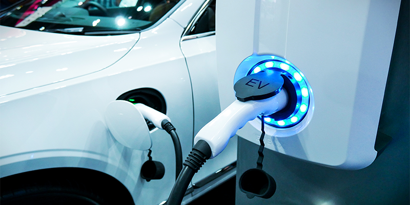A white electric vehicle next to a charging station.