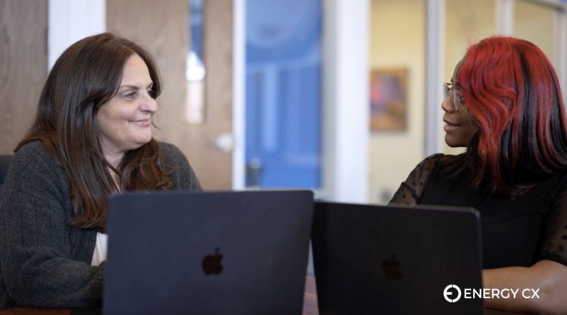 Rice smiles at a coworker as they talk over their laptops.