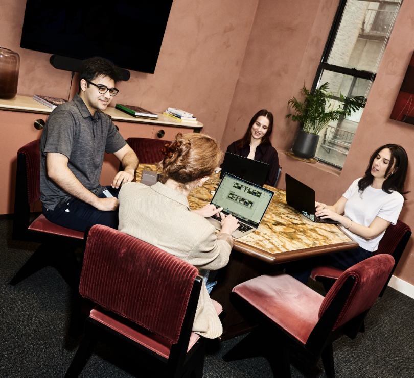 Four Genius AI employees collaborate on a project together in a conference room in the company’s office.&nbsp;