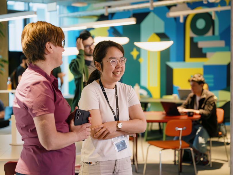 Two Grammarly team members laughing while chatting with each other in the office