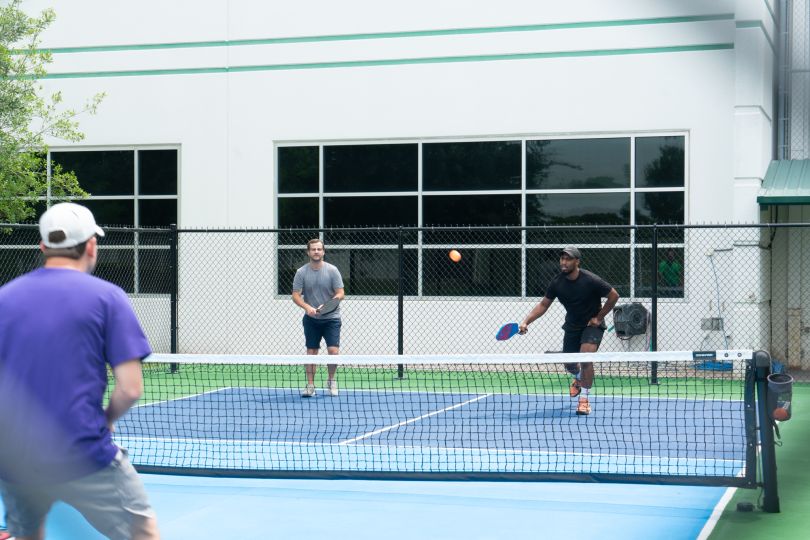 Three HCSS team members playing pickleball together on an outdoor court