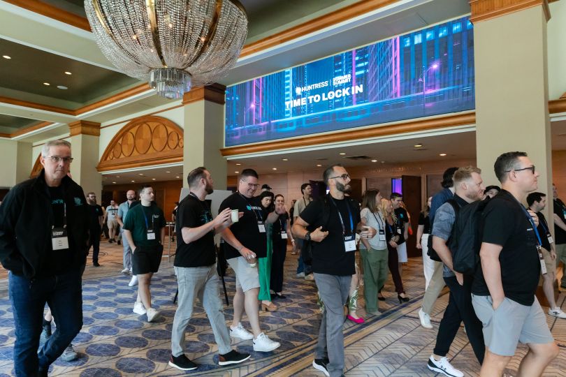 Huntress employees chat together while walking through a conference center during a company event.