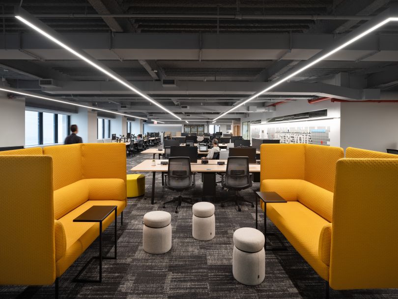A workspace in a Justworks office location that includes rows of tables equipped with computer monitors and two couches