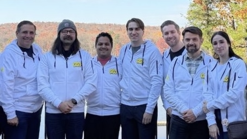 Several Kustomer team members pose for a group photo while wearing company-branded zip-up hoodies during GSD Week