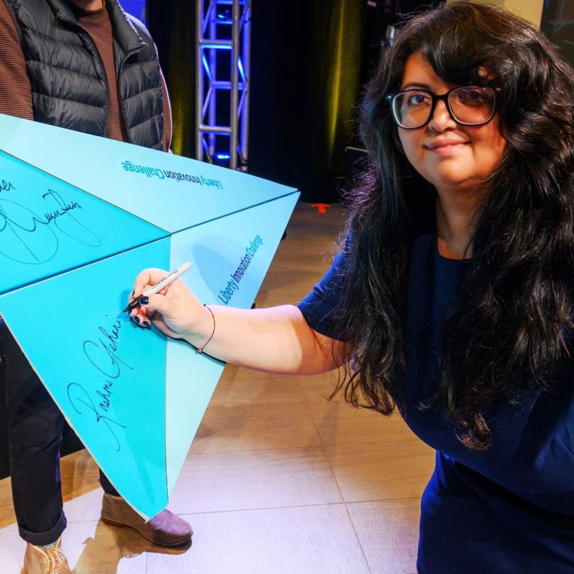 Rashmi Gehani signs her name on a board after winning the 2025 Liberty Innovation Challenge