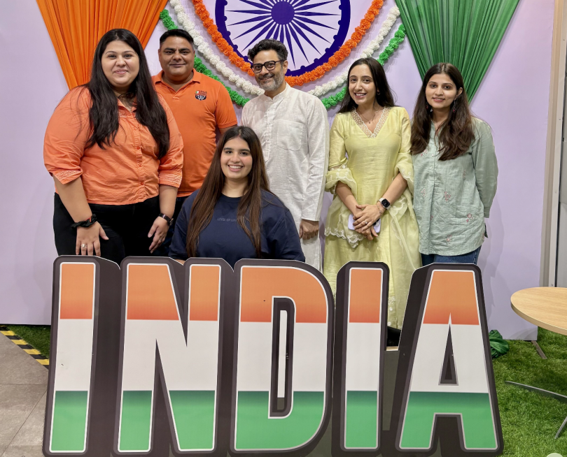 Several MongoDB employees pose for a photo behind multicolored letters that spell out  "India"