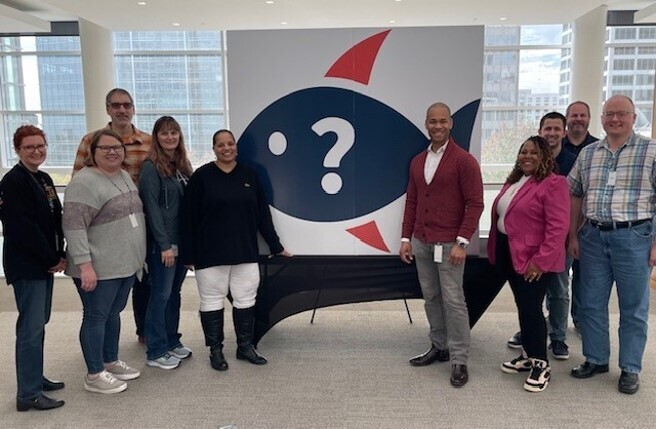 Northwestern Mutual team members standing beside a cybersecurity poster while posing for a group photo