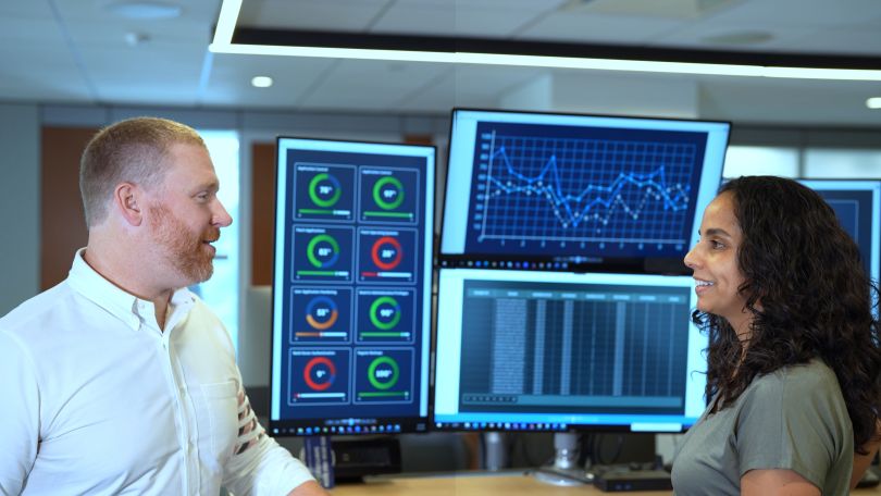 Pat Opet talks with CTC team member in front of multi-screen desk setup.