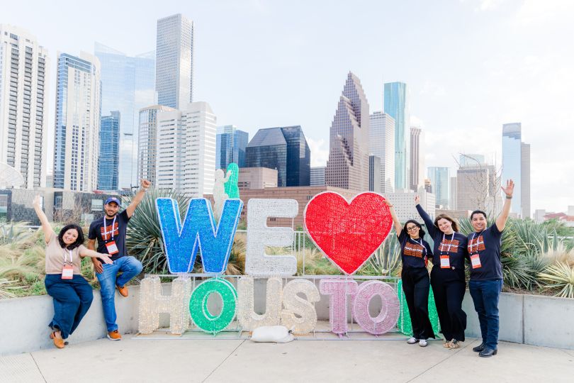 Several members of Toast’s Strategic Cuisines team pose for a photo beside an outdoor display that reads “We Love Houston”