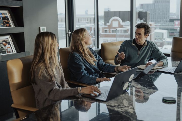 Three WHOOP employees discuss ideas for an ongoing project while seated at a table in a conference room in the company’s Boston office